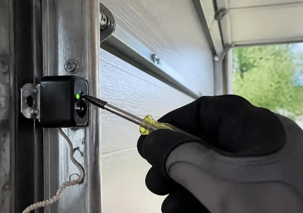 Technician adjusting a garage door sensor bracket in Bradenton, FL